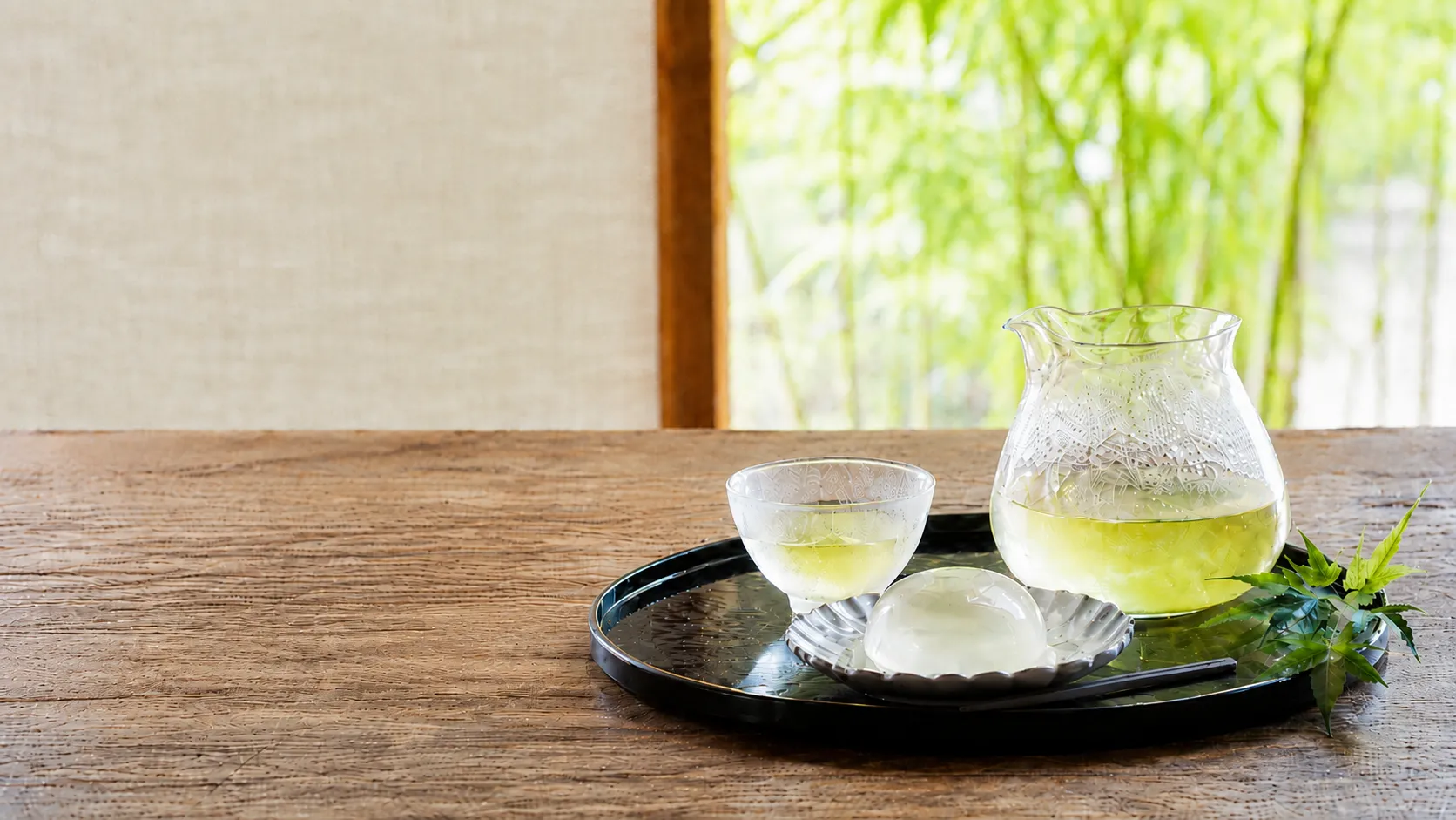 木のテーブルで湯呭みにお茶を注ぐ手元